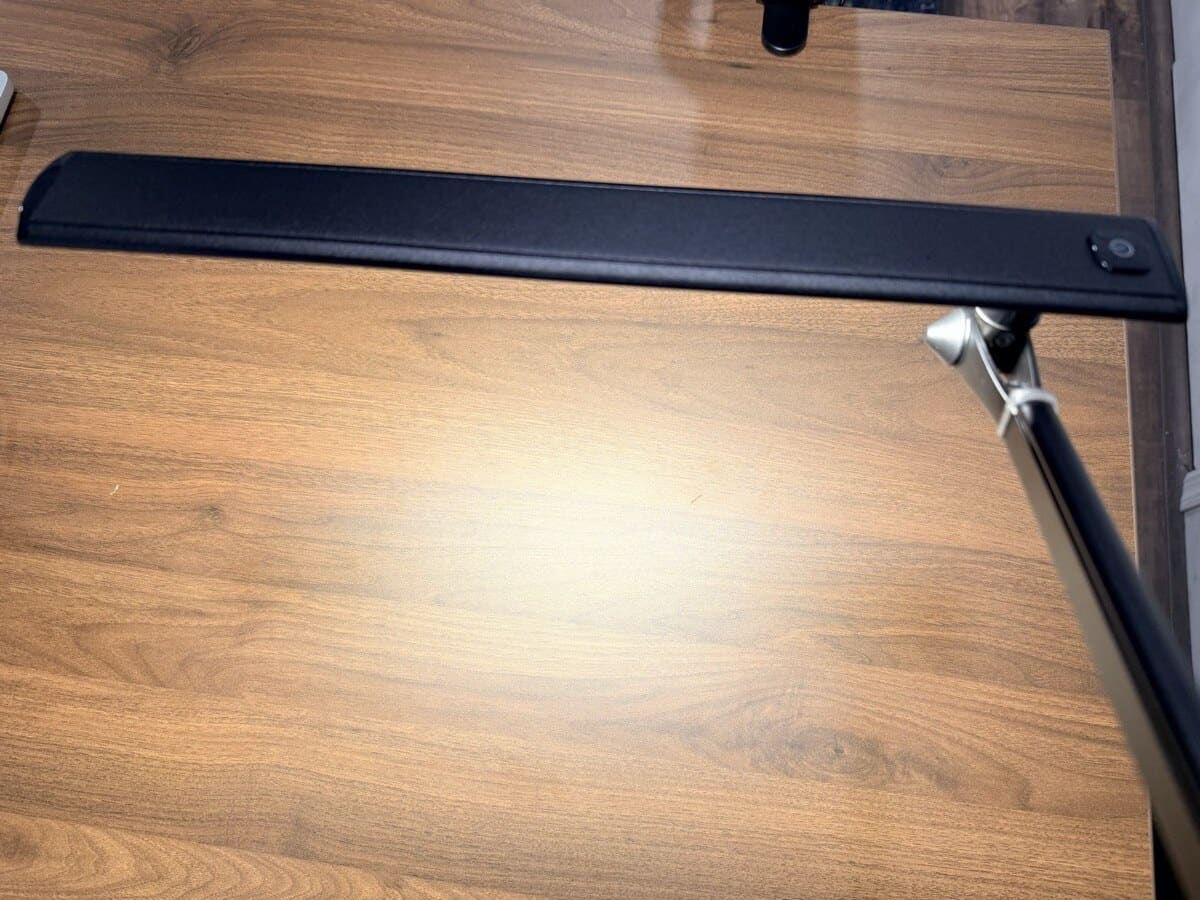UPLIFT E7 desk lamp in warm light mode on walnut desktop