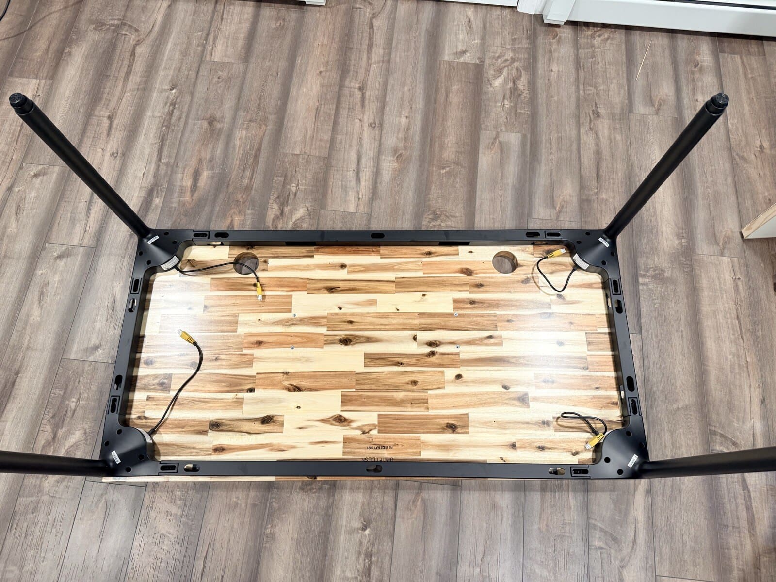 Frame assembled upside-down on the Acacia desktop with legs splayed out