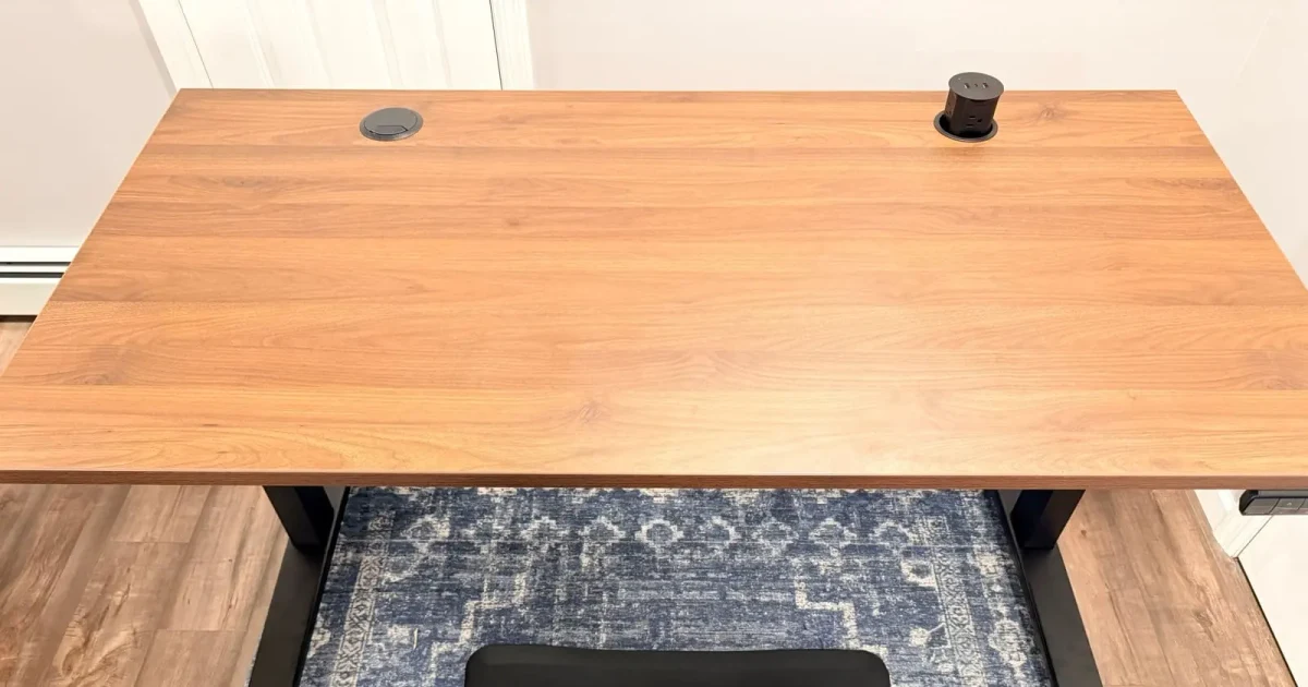 Top view of a 60 by 30 inch UPLIFT Walnut Laminate desktop with cable and power grommets