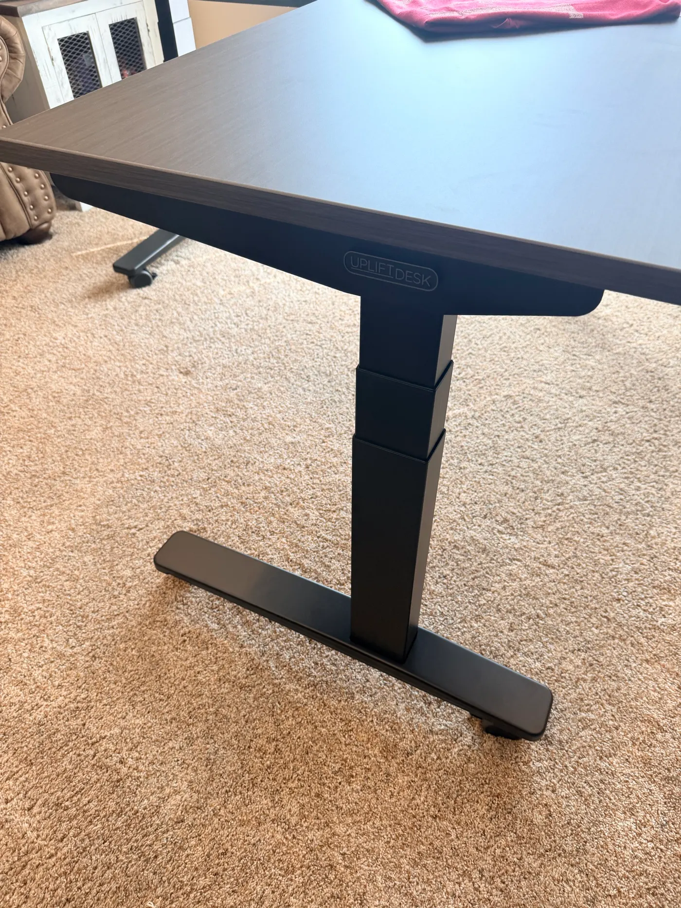 Close-up of the UPLIFT V3 L-Shaped frame leg and TremorGuard steel foot showing the wide ribbed footprint that resists side-to-side wobble at standing height