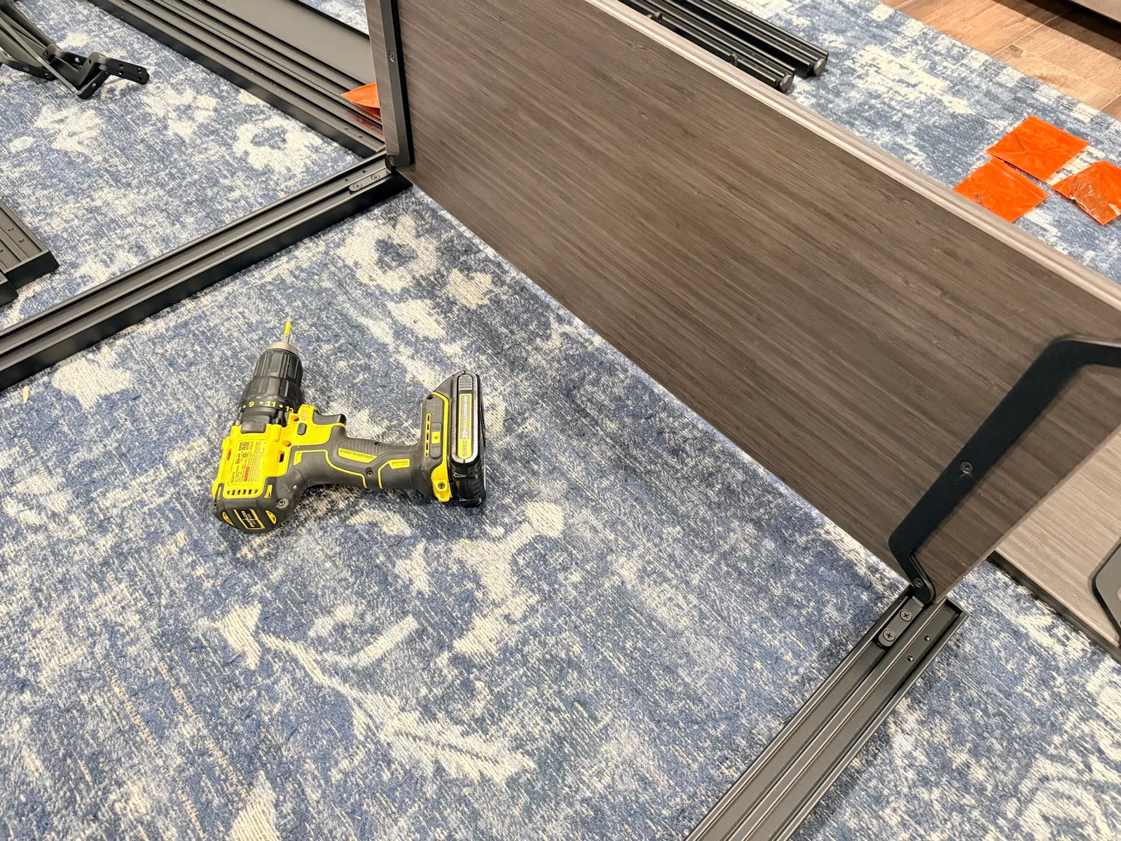 A cordless drill next to the Sequence Shelves frame pieces during assembly