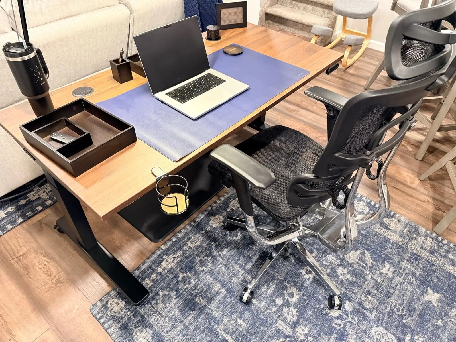 Standing desk, ergonomic chair, laptop, desk mat, and storage arranged as a complete workstation