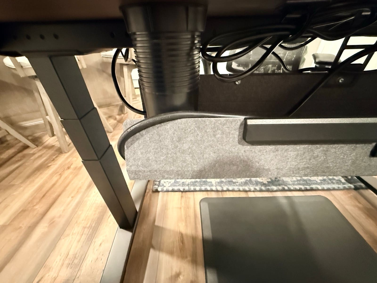 Under-desk view showing cable management tray, cables, and walking pad