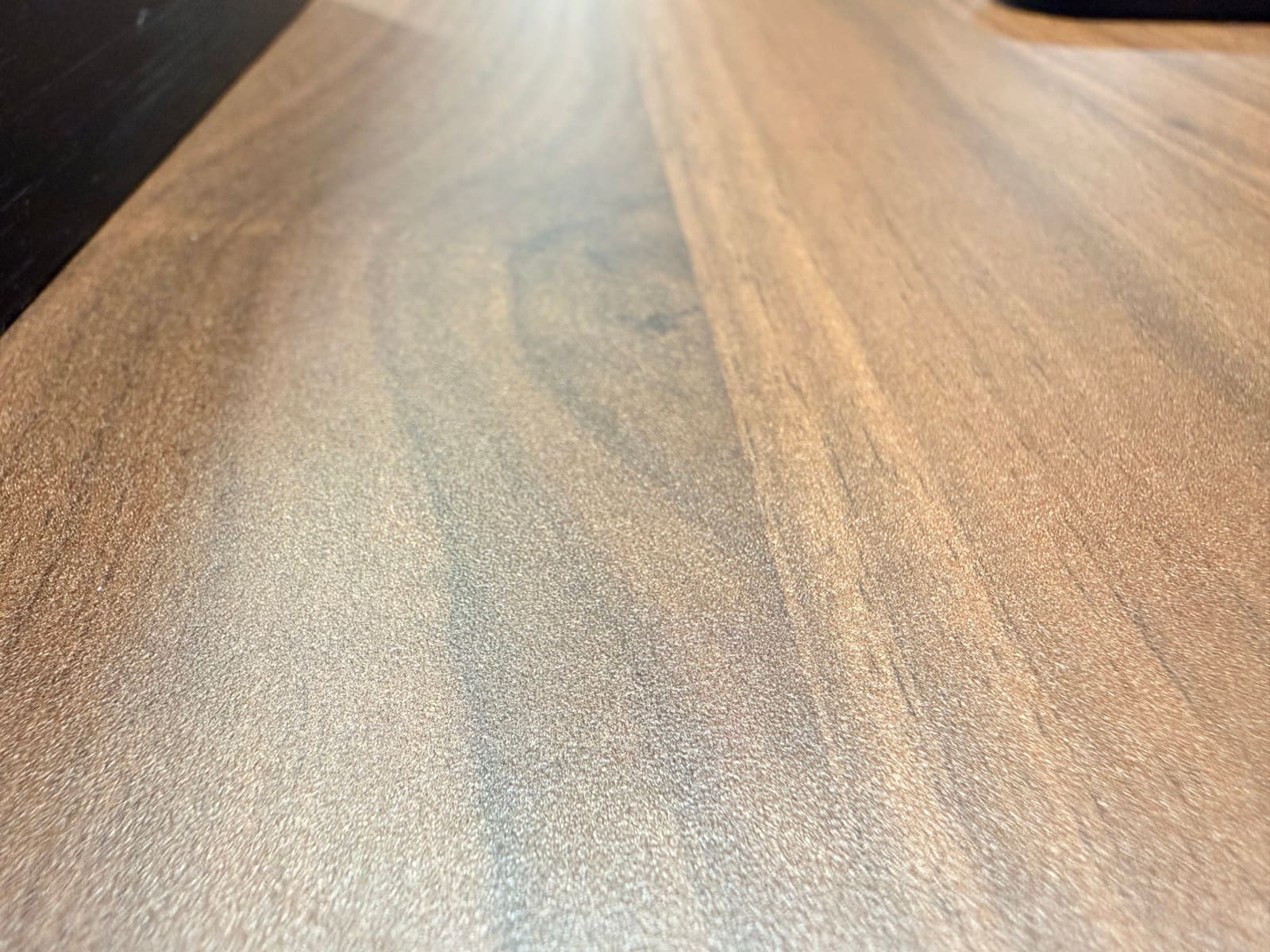 Close-up of walnut laminate desktop surface showing grain detail